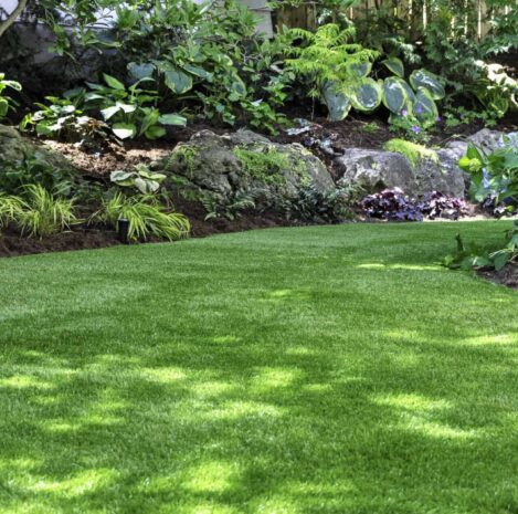 Artificial turf creates a natural look in a backyard garden. This beautiful backyard woodland garden features a maintenance free lawn made of realistic looking artificial grass, a huge landscaping trend for small spaces.